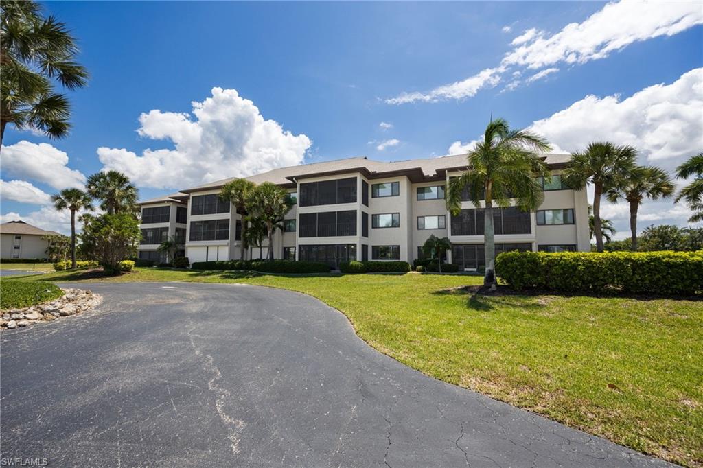Multi-story residential building featuring screened balconies, multiple windows, and a neutral exterior facade