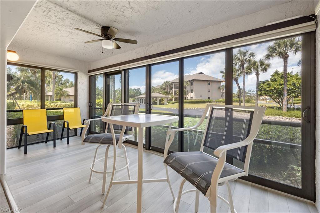 Screened lanai featuring wood-finish flooring, a ceiling fan with light, and extensive full-height screening