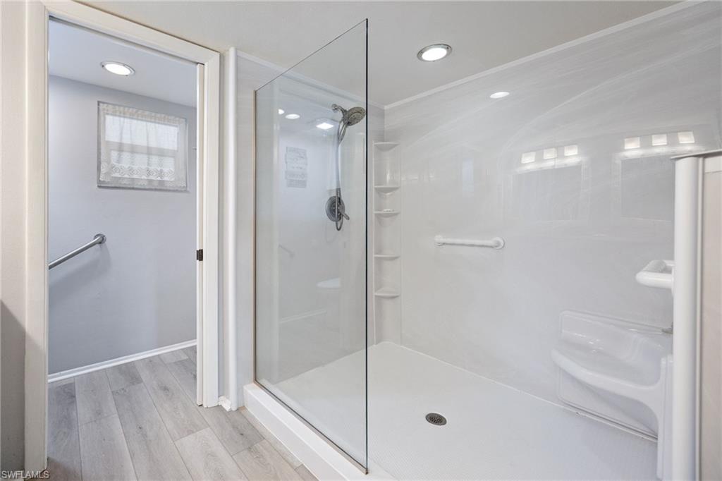 Walk-in shower with clear glass enclosure and white paneling