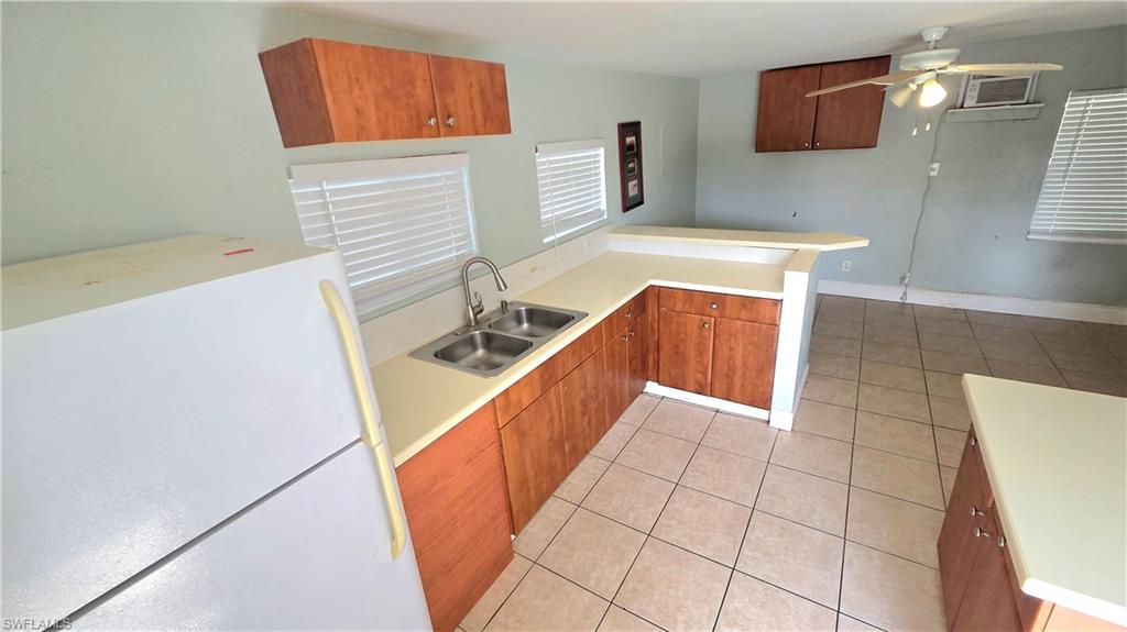 Guest House Kitchen area featuring a double basin sink, light-toned countertops, wood-finish cabinetry, and tiled flooring