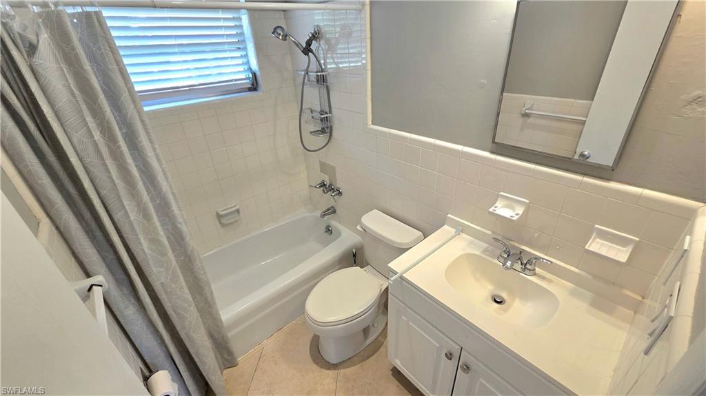 Bathroom #2  featuring a bathtub with shower fixture, white subway tile surround, white vanity with integrated sink, and an unframed mirror