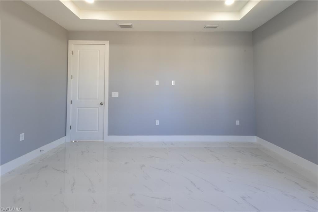 Spare room with light marble finish floors, recessed lighting, and a raised ceiling