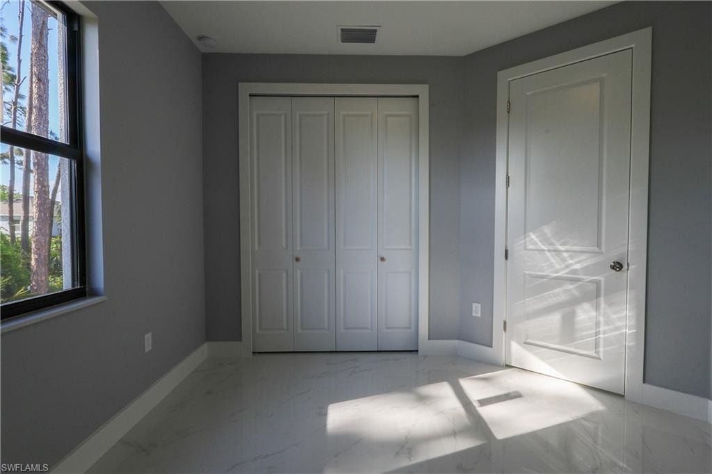 Unfurnished bedroom with light marble finish floors and a closet