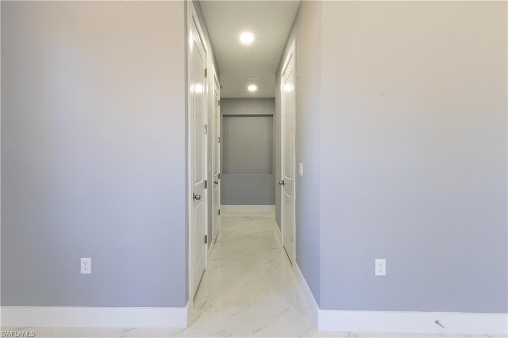 Corridor with light marble finish flooring and recessed lighting