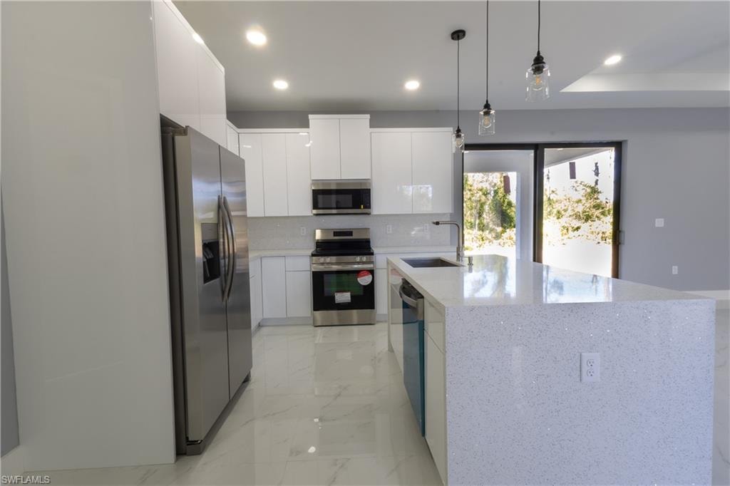 Kitchen with modern cabinets, appliances with stainless steel finishes, white cabinets, and recessed lighting