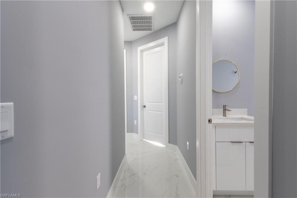 Hallway featuring light marble finish flooring and baseboards