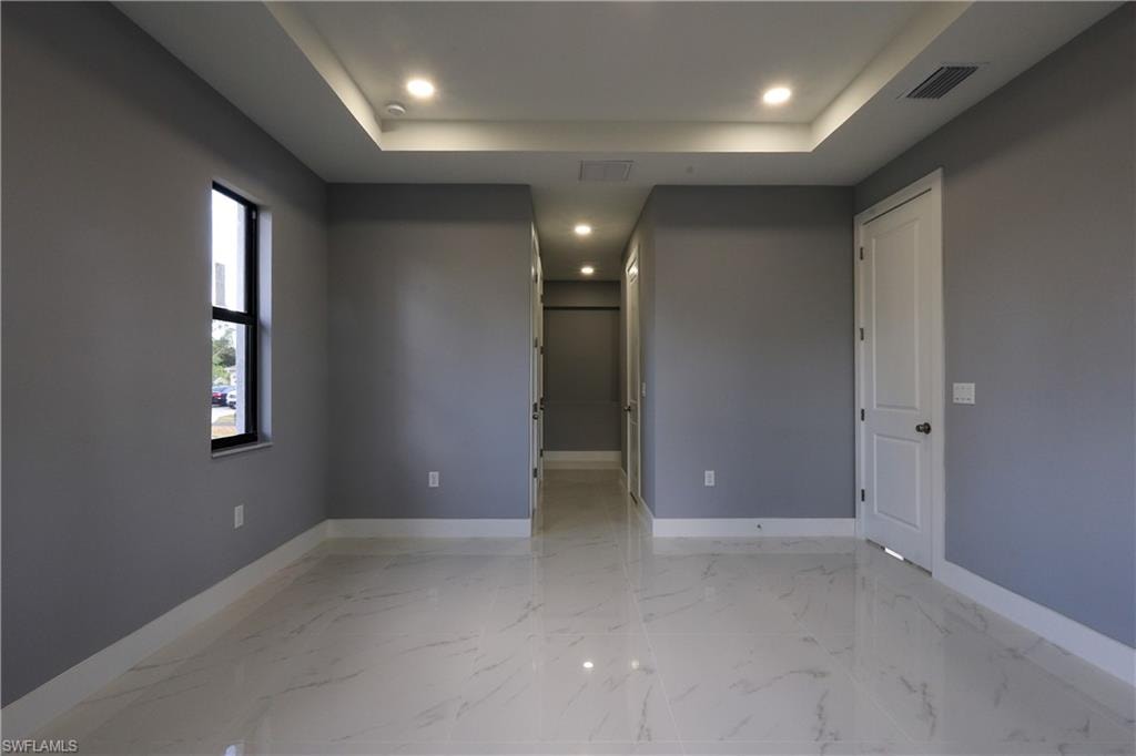 Unfurnished room with light marble finish floors, a raised ceiling, and recessed lighting