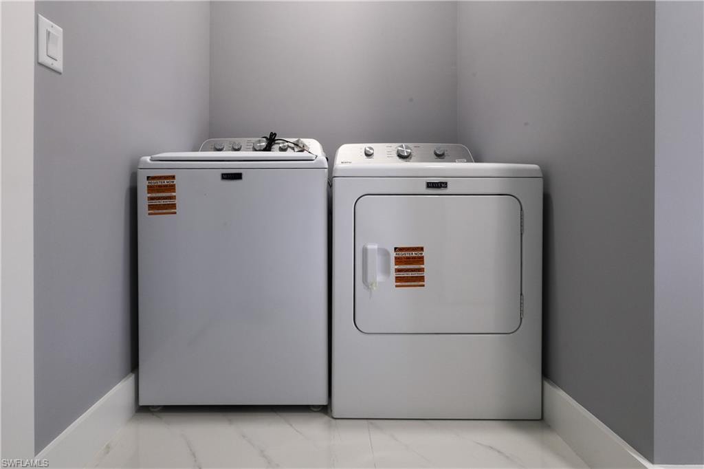 Laundry area featuring light marble finish floors and washing machine and dryer