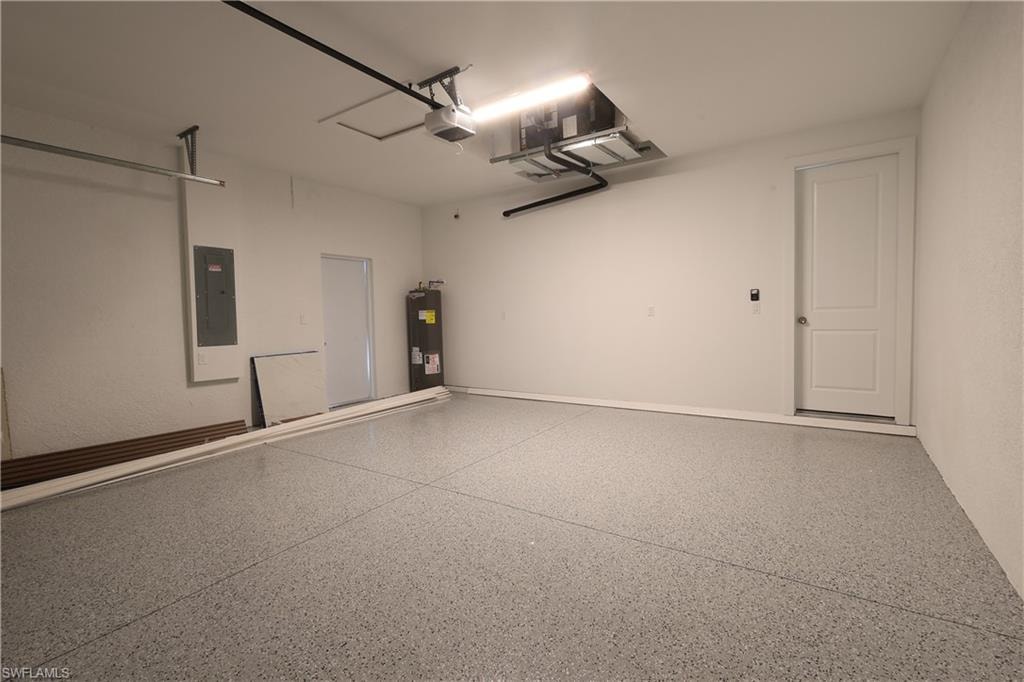 Garage with electric panel, water heater, and a garage door opener