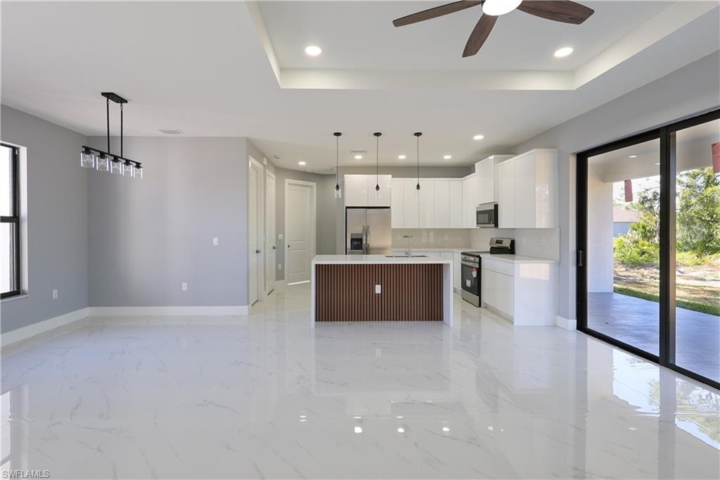 Kitchen featuring plenty of natural light, a center island with sink, decorative light fixtures, white cabinetry, and recessed lighting