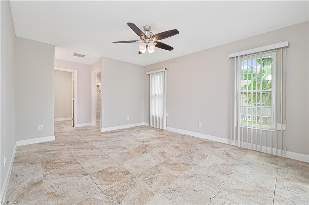 Spacious room featuring neutral wall tones, large format tile flooring, a ceiling fan with integrated lighting, and multiple windows with vertical blinds