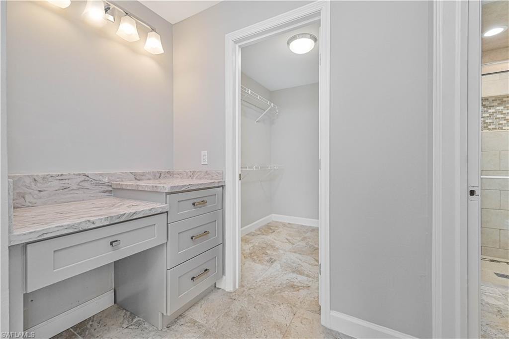 Built-in vanity with light grey cabinetry and stone countertops