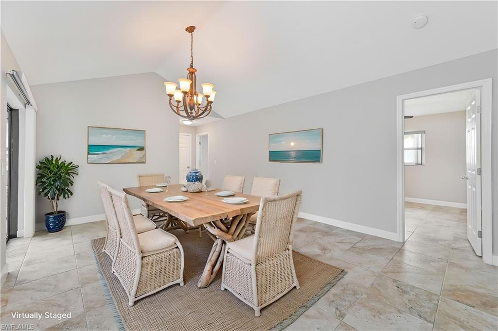 Dining area featuring vaulted ceilings, a central chandelier, and large format tile flooring