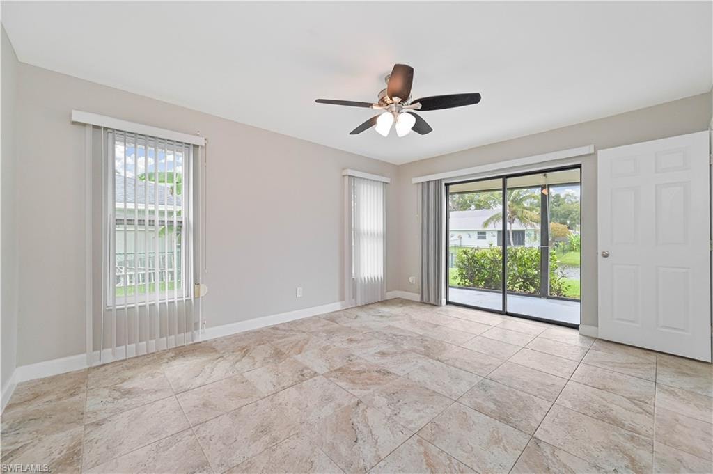 Spacious room featuring neutral tone walls, large format tile flooring, a ceiling fan, and sliding glass doors opening to a screened outdoor area