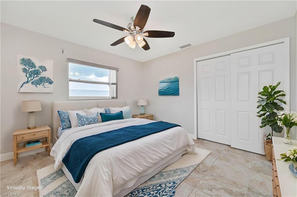 Bedroom featuring a window with water scenery, tile flooring, a ceiling fan, and sliding closet doors