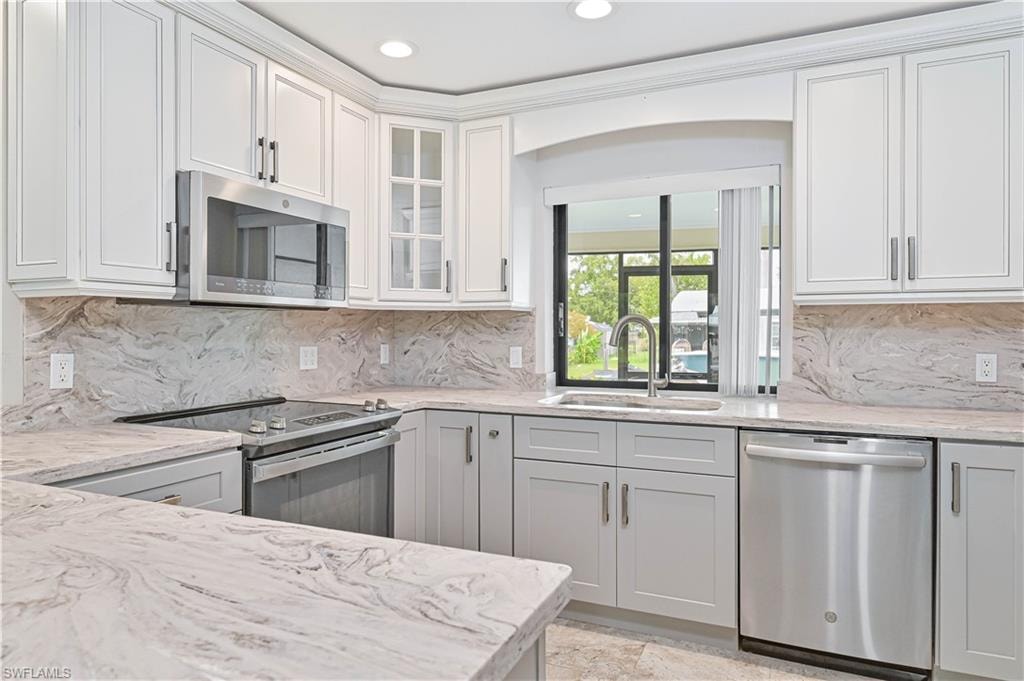 Kitchen featuring light-toned cabinetry, stainless steel appliances, and stone countertops