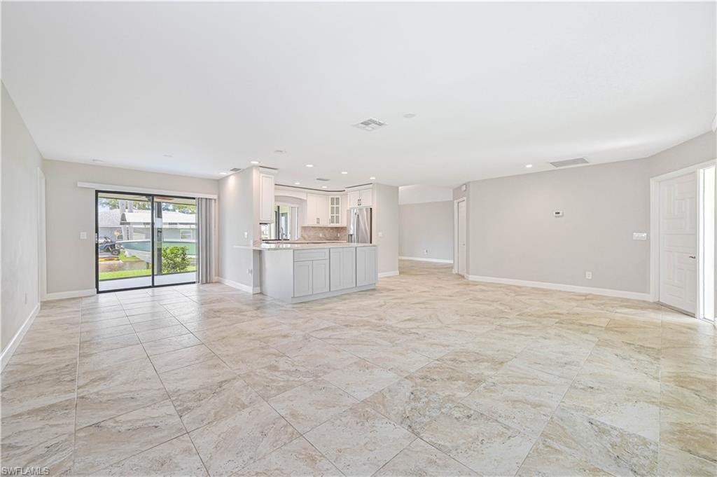 Open-concept living space featuring large format tile flooring, light neutral wall paint, and recessed lighting