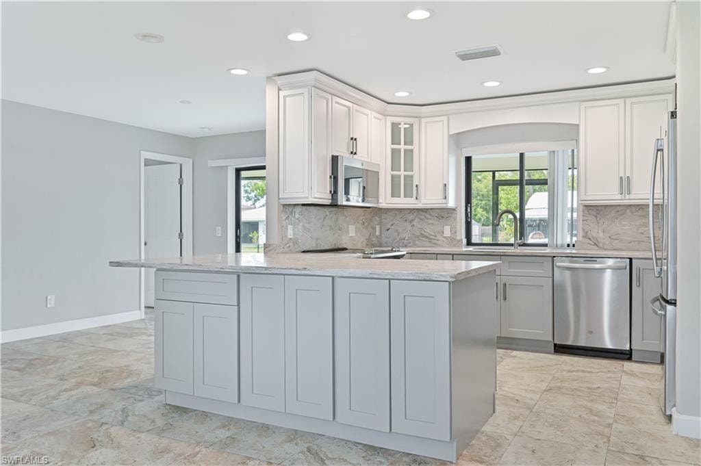 Central kitchen island with an extended countertop for seating, complemented by recessed lighting and light-toned cabinetry