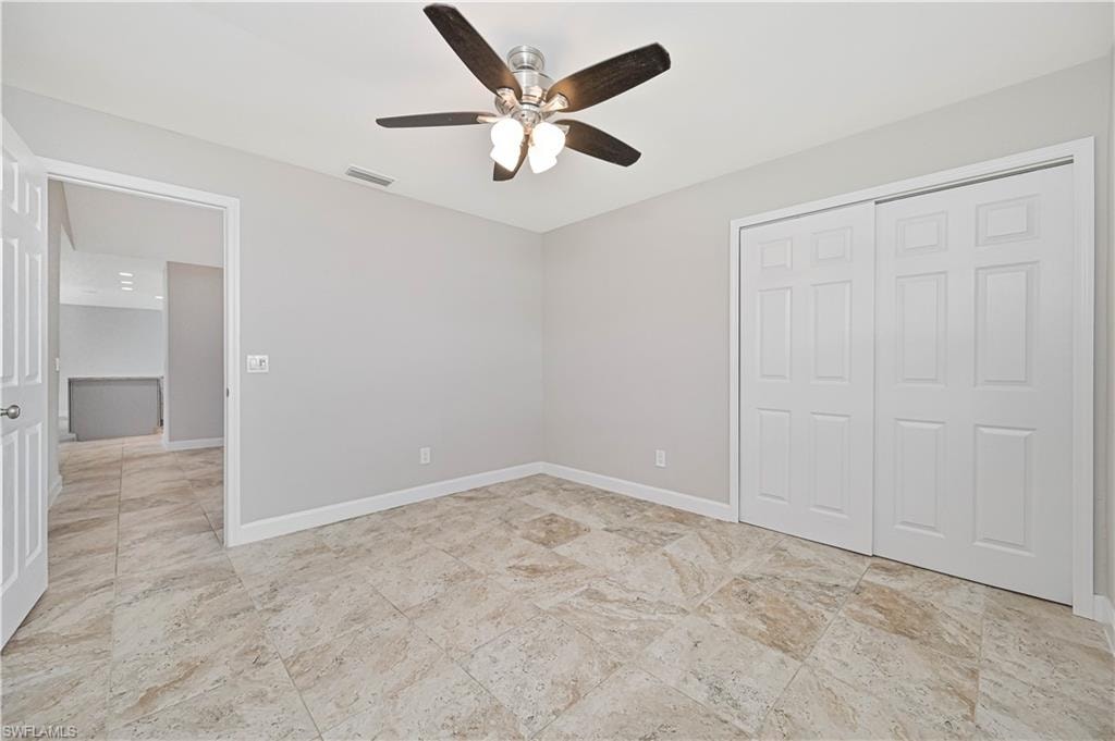 Room featuring large-format tile flooring, a ceiling fan with integrated lighting, and a bi-fold closet with paneled doors