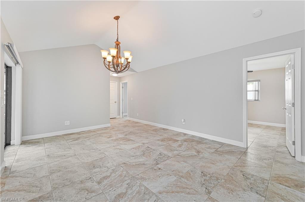 Spacious room featuring vaulted ceilings, neutral wall paint, and large format tiled flooring