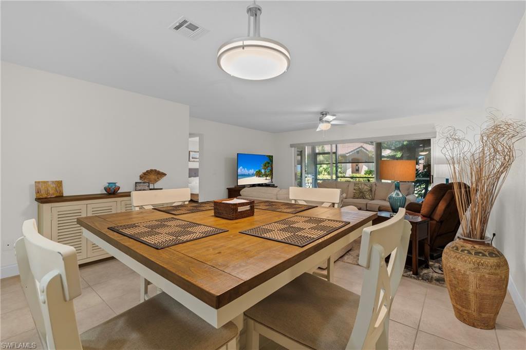 Open-concept living space with tile flooring throughout, featuring a dining area with a wood-finish table and a living area with large windows