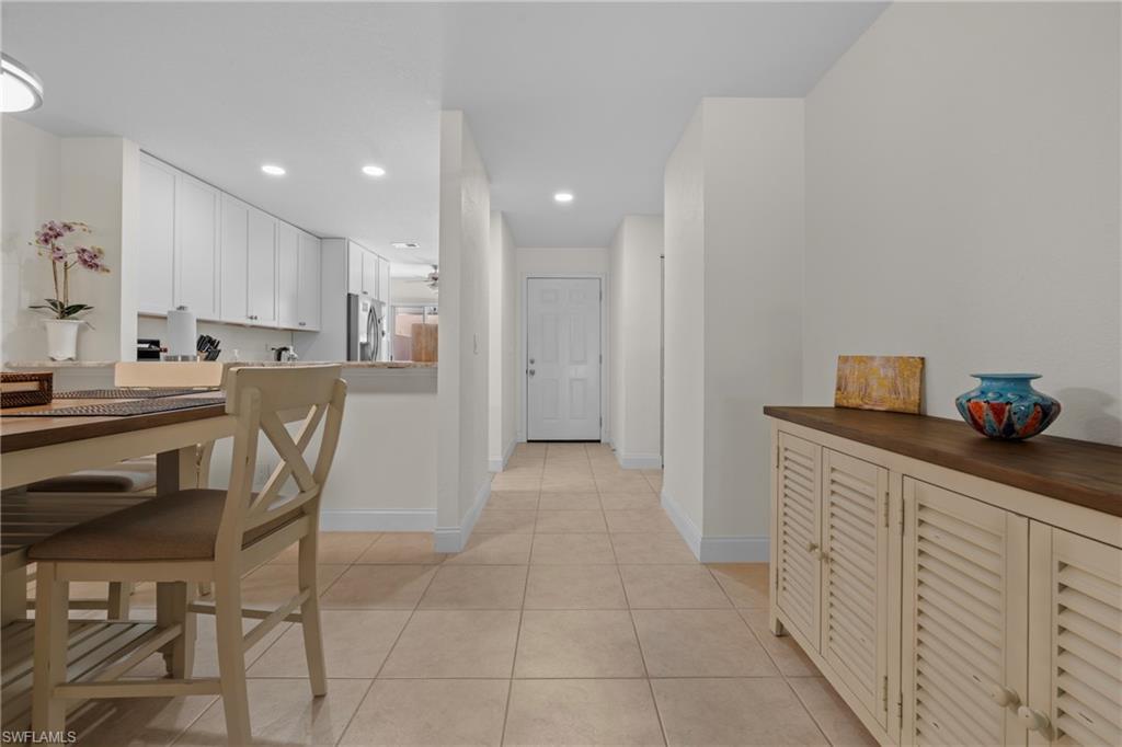 Hallway with light-colored tile flooring leading to a white entry door