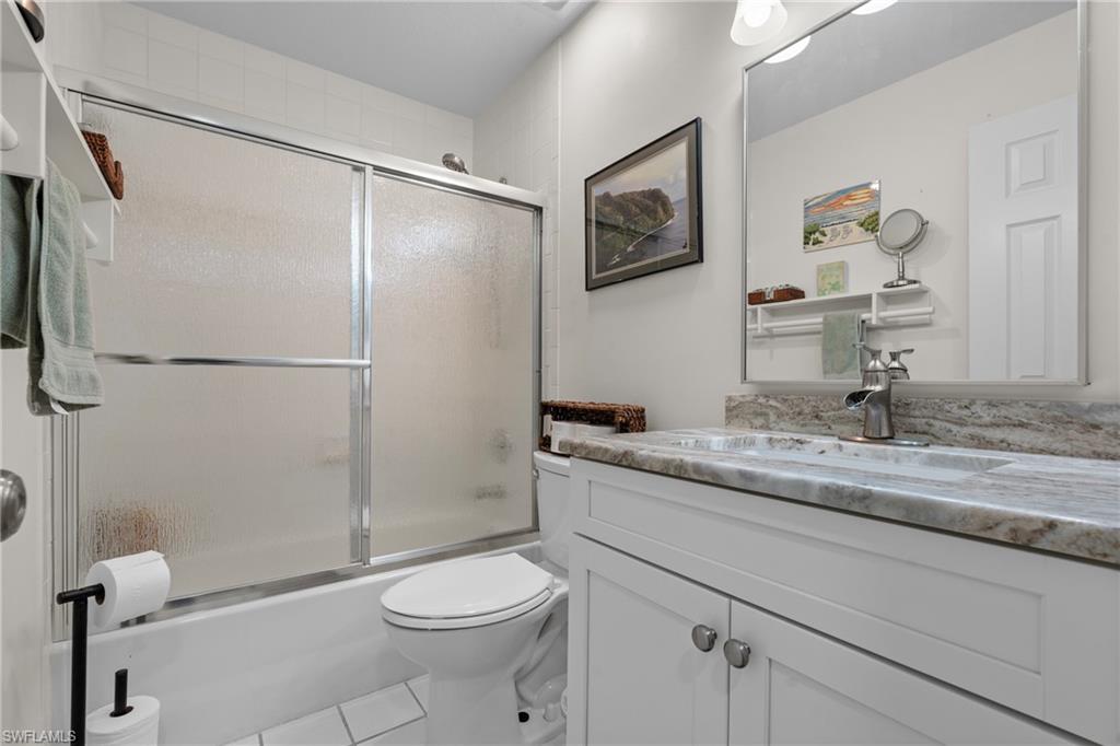 Bathroom featuring a white vanity with a stone-finish countertop and integrated sink