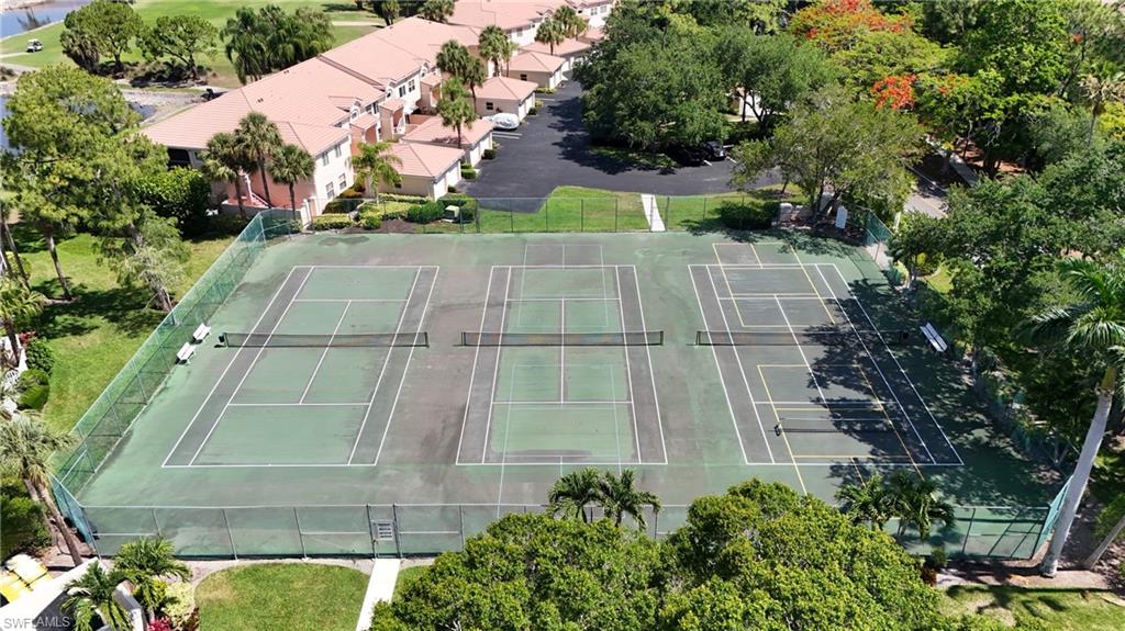 Fenced tennis courts featuring multiple playing areas and surrounding mature landscaping