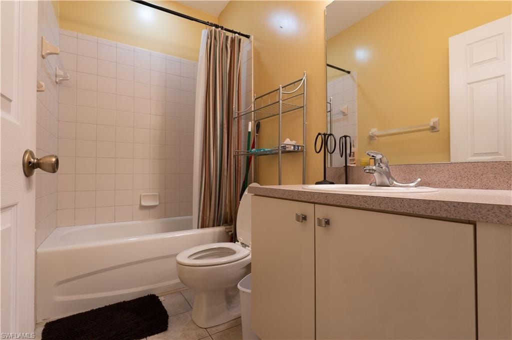 Full bathroom featuring toilet, shower / tub combo, vanity, and tile patterned floors