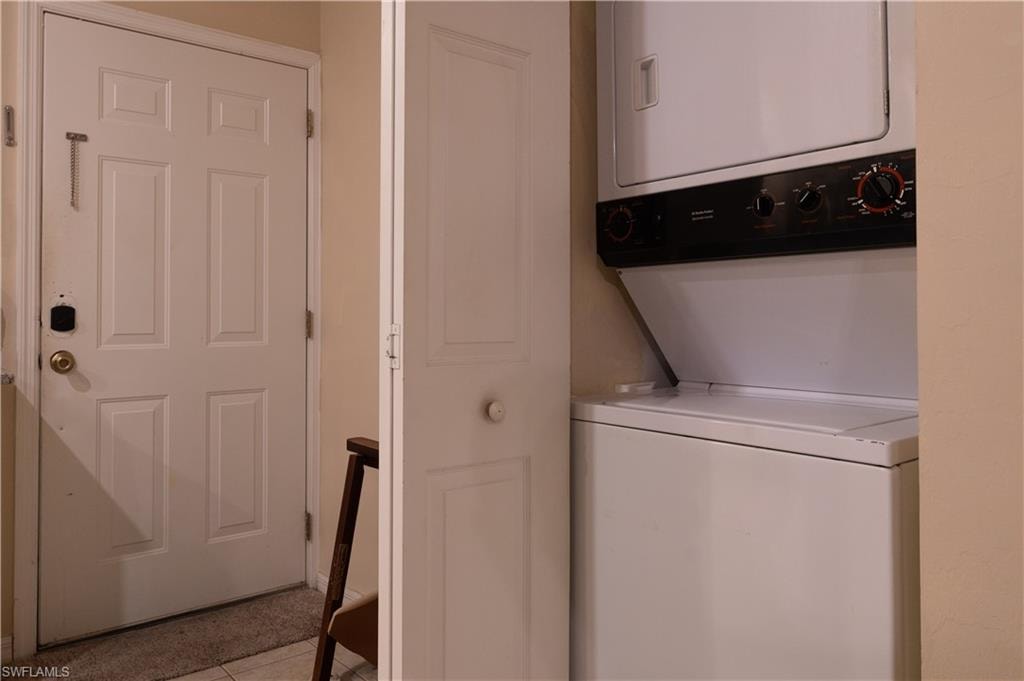 Laundry area with light tile patterned floors and stacked washer and dryer