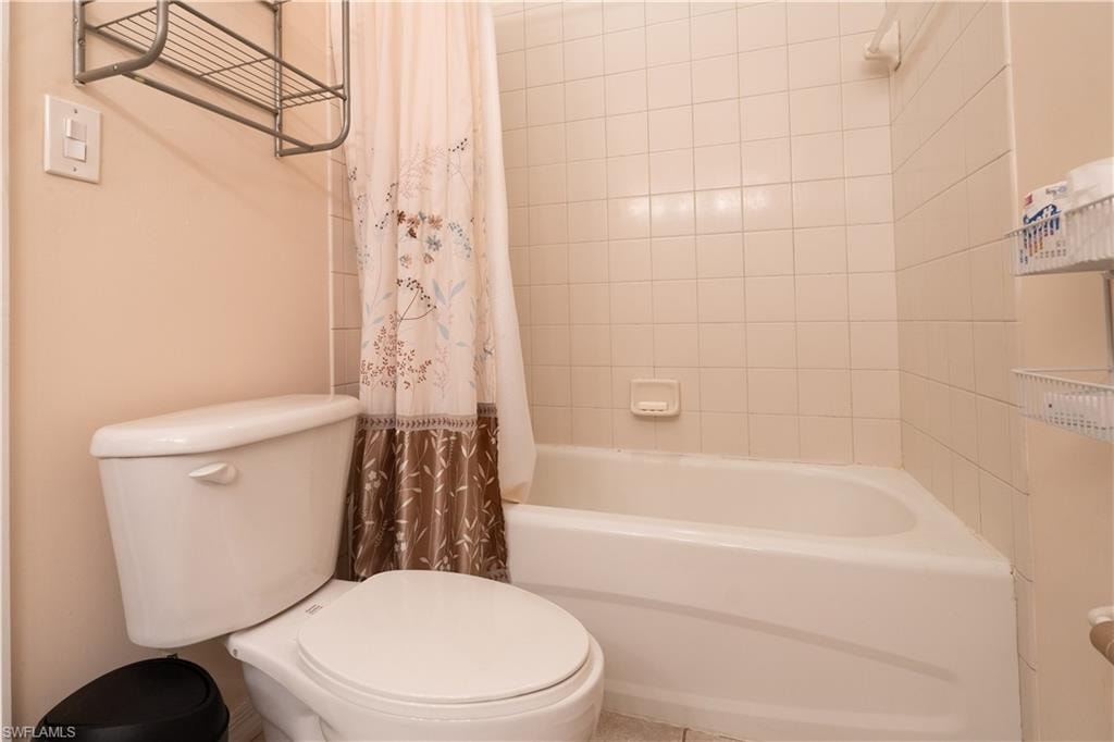 Bathroom featuring shower / bathtub combination with curtain and toilet