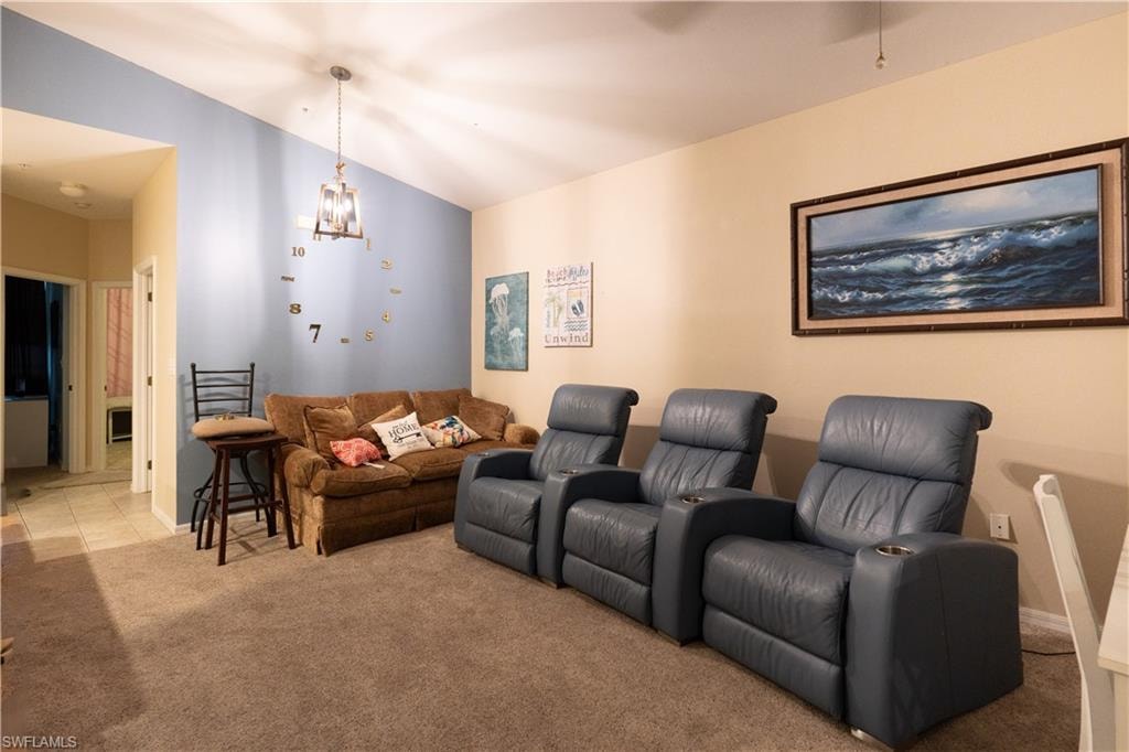 Home theater room with lofted ceiling, a chandelier, and light colored carpet