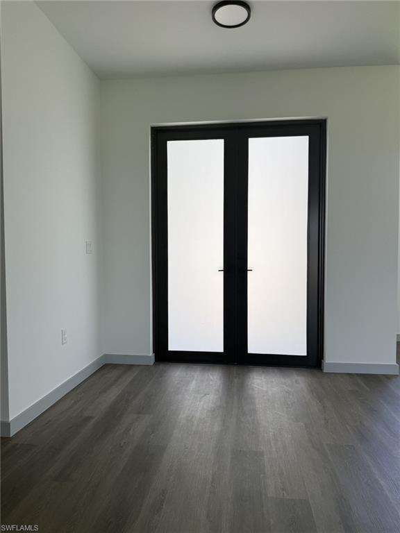Room featuring dark-framed double doors with frosted glass panels, wood-finish flooring, white walls, and a contemporary ceiling light fixture