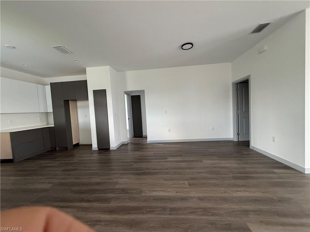 Open-concept living space featuring wood-finish flooring, white walls, and contemporary baseboards