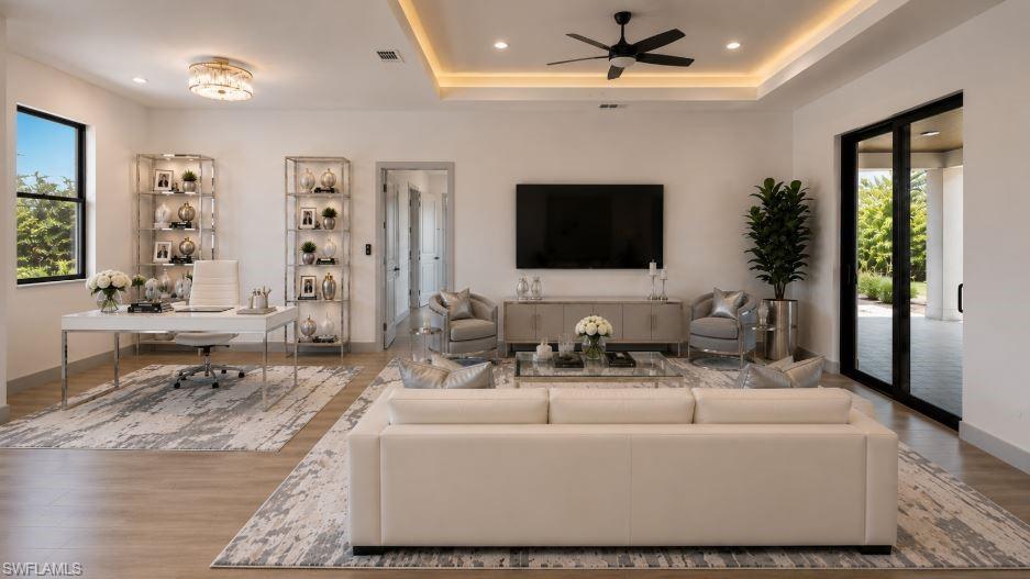 Expansive living area featuring light wood-finish flooring, recessed lighting, and a tray ceiling with accent lighting