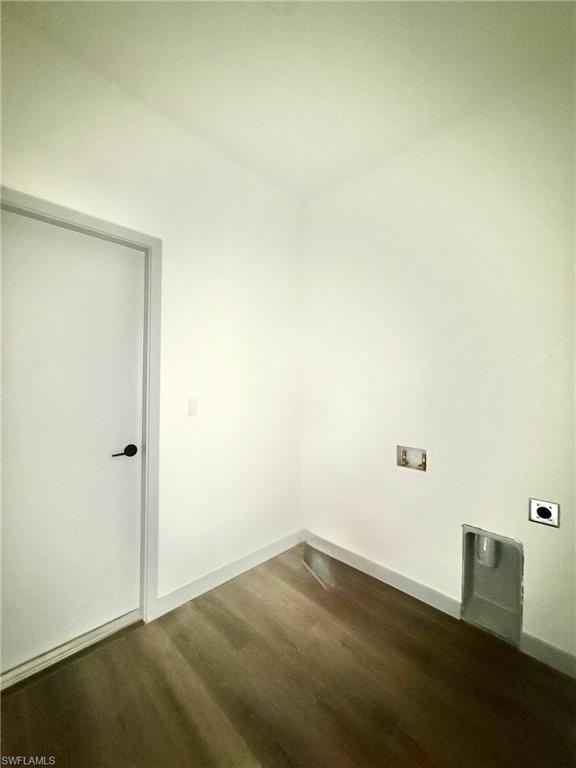 Dedicated utility space featuring wood-finish flooring, white walls, and a door with black hardware