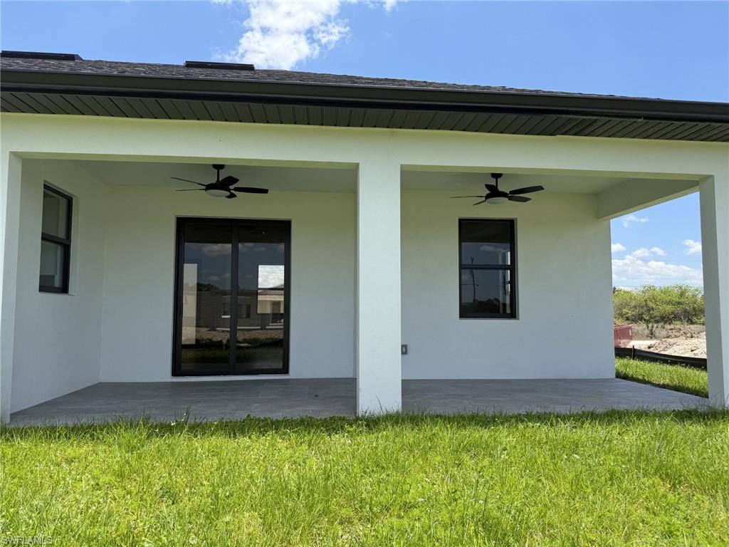 Expansive covered trussed in lanai featuring dual ceiling fans, a sliding glass door, and a large window
