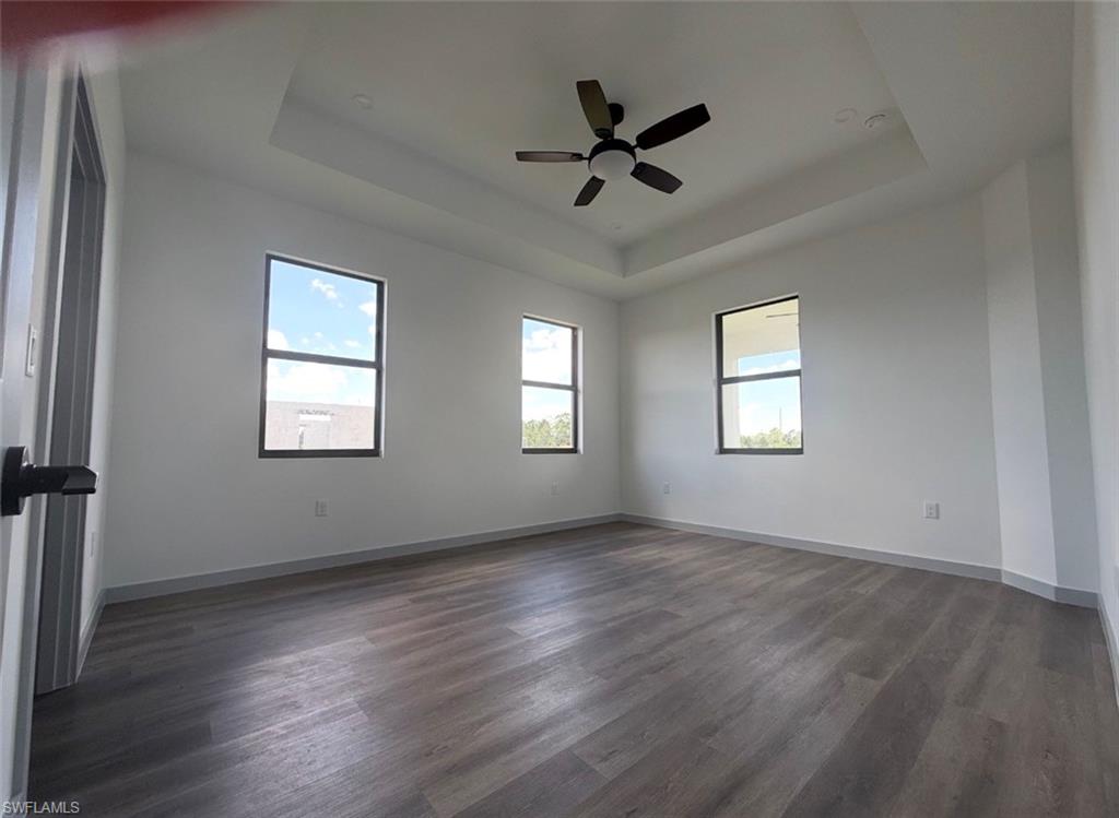 Spacious master bedroom w/space for sitting area featuring tray ceiling and a ceiling fan
