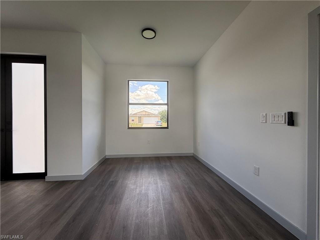 Room featuring wood-finish flooring, a contemporary ceiling light fixture, a window with a black frame, and a tall door with a frosted panel