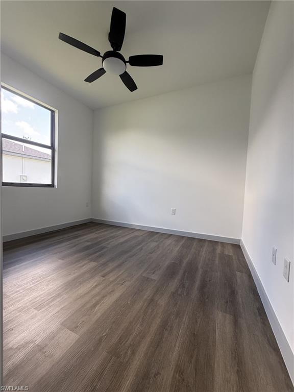 Spacious room featuring wood-finish flooring, a contemporary ceiling fan with integrated lighting, and a large window providing natural light