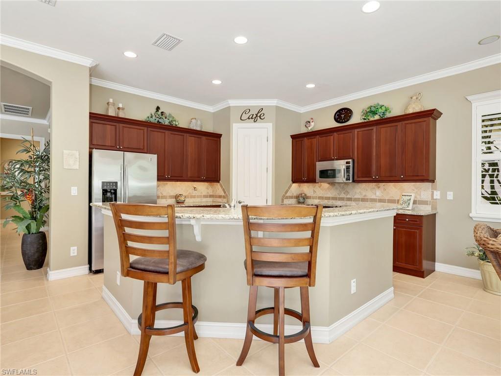 Kitchen with 42" Cabinetry, Crown Molding, Stainless Steel Appliances, Granite Countertops, Tile Backsplash, Crown Molding, & Pantry