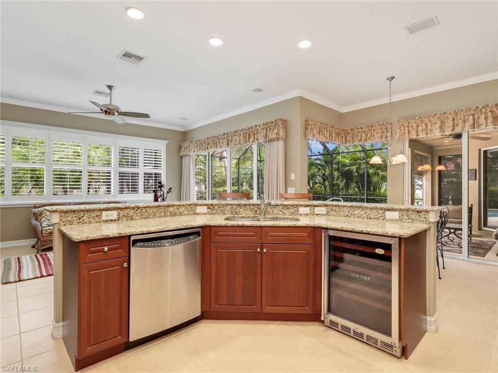 Kitchen with Stainless Steel Appliances, Wine Fridge, Granite Countertops, Breakfast Bar, Family Room & Eat-In Kitchen with Sliders Leading to the Screened-Lanai with a Pool View