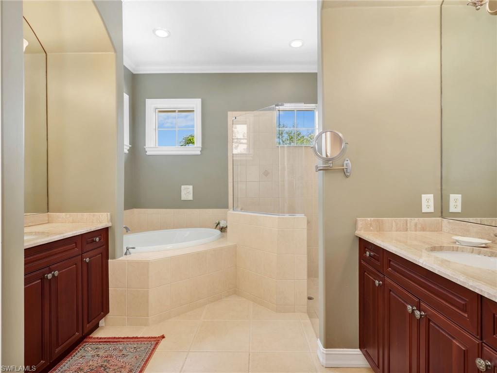 Primary En-Suite Bathroom with Crown Molding, Dual Vanities & Sinks, Cultured Marble Countertops, Separate Tub, & Walk-In Shower with Glass Enclosure