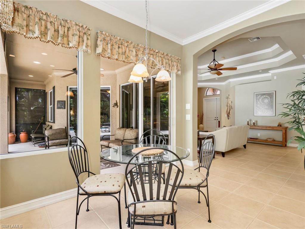 Eat-In Kitchen with Crown Molding & Sliders Leading to the Screened-In Lanai with a Pool View, & Formal Living Room with Tray Ceiling, Crown Molding, & Ceiling Fan