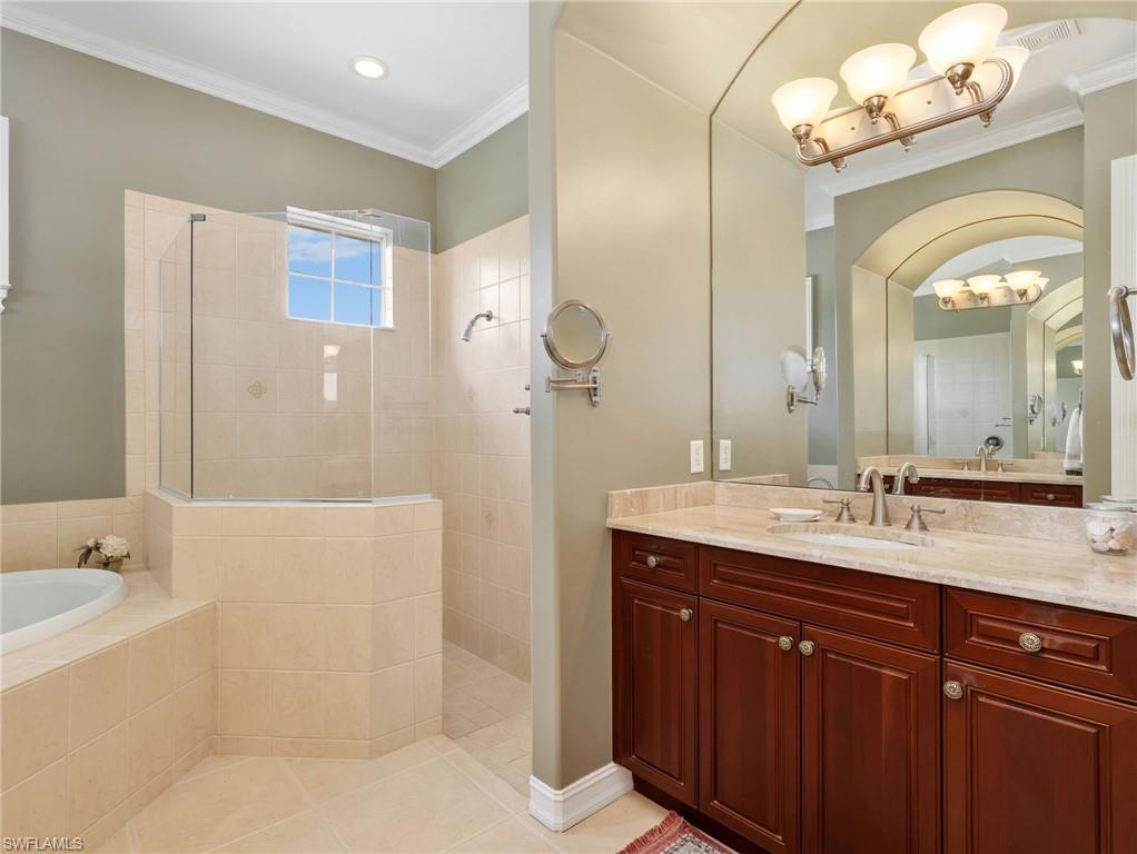 Primary En-Suite Bathroom with Crown Molding, Dual Vanities & Sinks, Cultured Marble Countertops, Separate Tub, & Walk-In Shower with Glass Enclosure