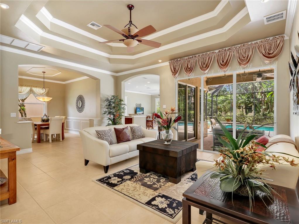 Formal Living Room with Crown Molding, Tray Ceiling, & Sliders Leading to the Screened-In Lanai with a Pool View & Dining Room with Crown Molding, Chair Railing with Picture Molding Detail & Decorative Ceiling Molding
