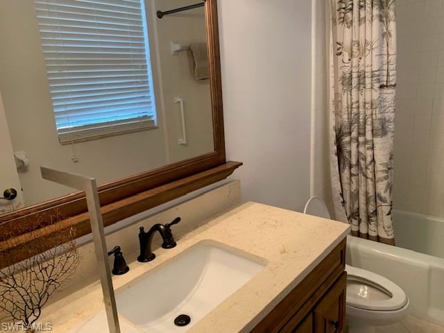 Full bathroom featuring vanity, toilet, and shower / bathtub combination with curtain