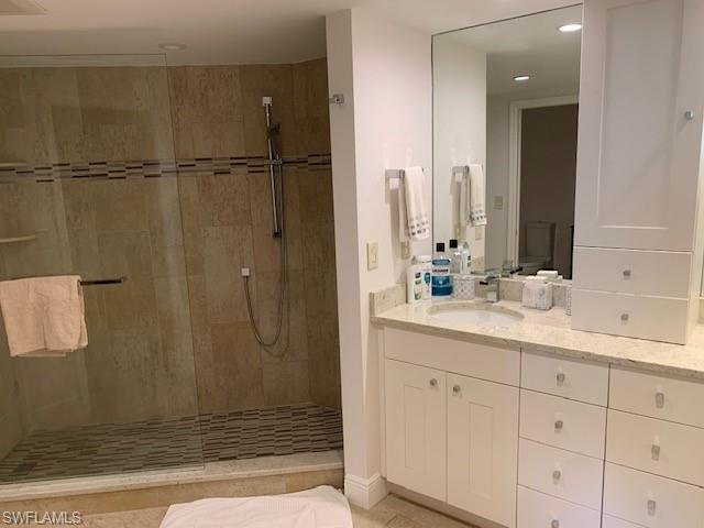 Bathroom featuring vanity, a tile shower, and tile patterned flooring