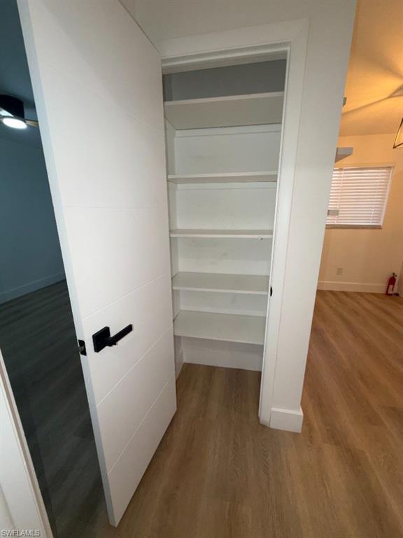 Built-in storage closet featuring multiple white shelving units and a modern white paneled door with black hardware