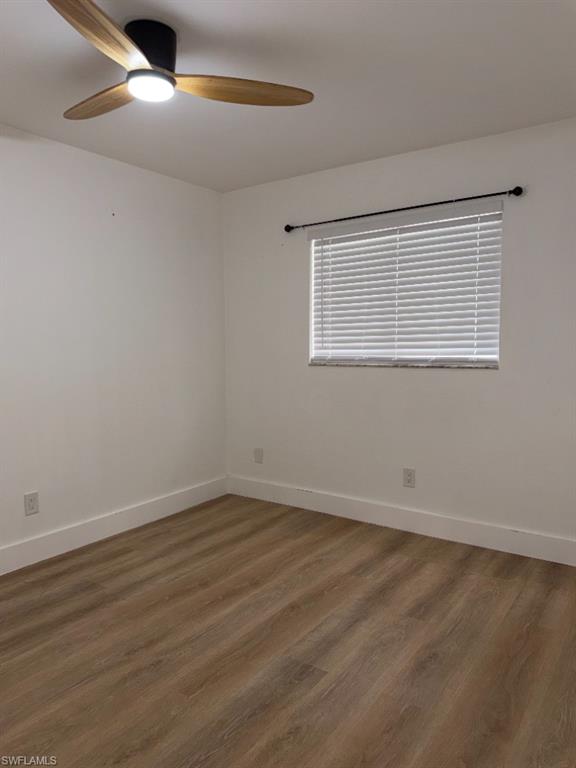 Room featuring wood-finish flooring, white walls, and white baseboards